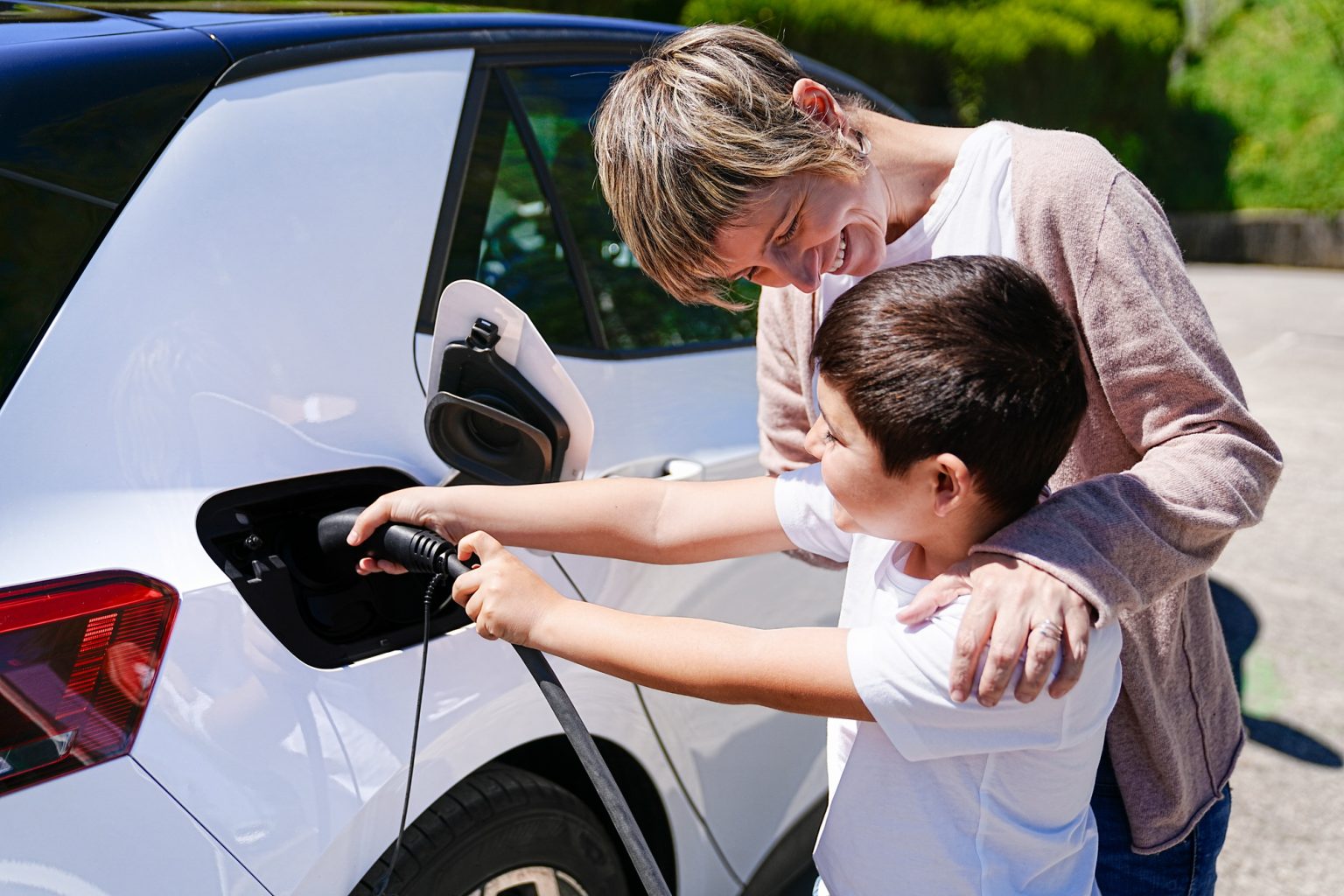 Mother and Son's Playful Collaboration at EV Charging Station